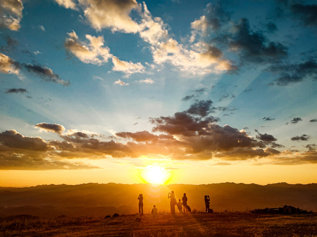 The image may depict a group of travelers walking along a path as the sun sets on the horizon. It symbolizes determination, the search for meaning, or the transition between the end of one day and the beginning of another.