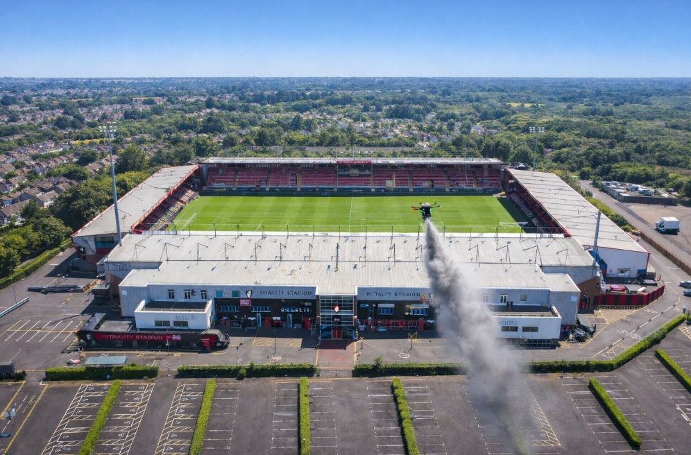Aerial view of Vitality Stadium, featuring a green pitch and surrounding trees under a clear sky.
